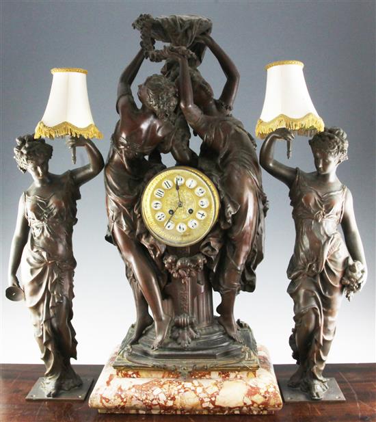 An early 20th century bronzed spelter clock garniture, clock 30in. flanking lamps 24in.